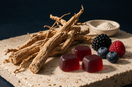 Editorial illustration of ashwagandha roots, berry gummies, mixed berries and a spoon of white powder